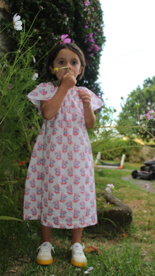 Young girl in a floral dress standing in a garden